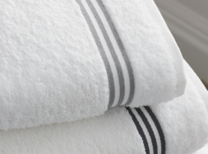 Zwei gefaltete weiße Handtücher mit grauen Streifen liegen übereinander.